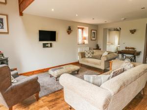 a living room with two couches and a tv at Barn Owl Cottage At Crook Hall Farm in Mawdesley