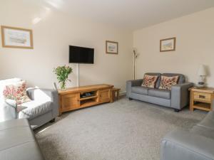 uma sala de estar com dois sofás e uma televisão em Sandlings em Hollesley