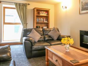 a living room with a leather couch and a coffee table at Dover Barn in Parwich