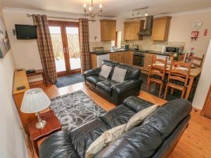 a living room with a leather couch and a kitchen at The Stall in Llanmorlais