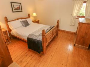a bedroom with a bed and a wooden floor at The Stall in Llanmorlais