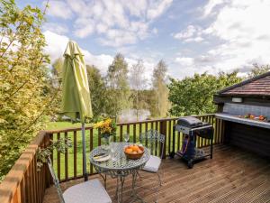 a patio with a table and a grill on a deck at The Stilehouse Apartment in Pensax