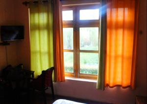 a window with orange and yellow curtains in a room at Hotel Ladakh Heaven in Leh