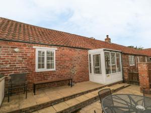 a brick house with a patio with a bench at Little Argham Cottage in North Burton