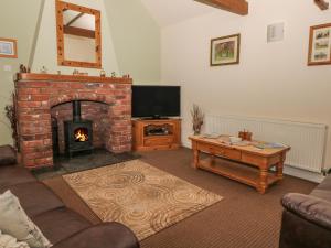 a living room with a brick fireplace and a television at Little Argham Cottage in North Burton