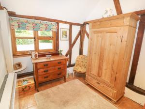 Habitación con armario de madera, cómoda y ventana en The Pottery en Urchfont