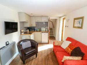 een woonkamer met een rode bank en een stoel bij Chequer Stable in Brereton cum Smethwick