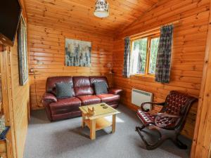 a living room with a leather couch and a table at The Spinney Lodge in Jedburgh