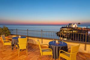 a patio with two tables and chairs and the ocean at Hotel Nettuno in Ischia