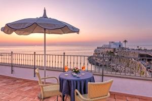 a table on a balcony with an umbrella and the ocean at Hotel Nettuno in Ischia