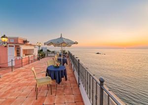 a patio with tables and an umbrella and the ocean at Hotel Nettuno in Ischia