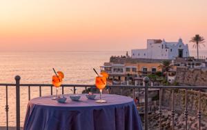 a table with two glasses of oranges on top of the ocean at Hotel Nettuno in Ischia