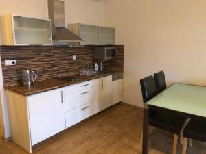 a kitchen with white cabinets and a table with a tableablish at L&B Lake view modern apartment in Lipno nad Vltavou