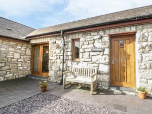 a wooden bench sitting outside of a stone cottage at Cwt Blawd in Llangoed