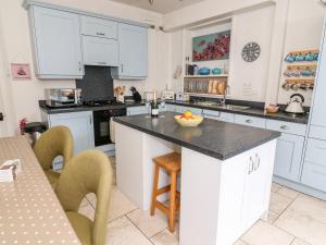 uma cozinha com armários brancos e um balcão preto em Canalside Cottage em Kildwick
