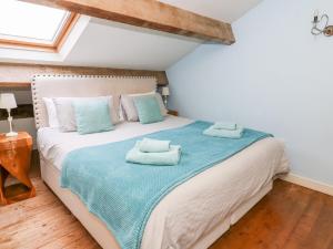 um quarto com uma cama grande e toalhas em Canalside Cottage em Kildwick