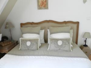 een slaapkamer met een bed met witte kussens bij Le Pressoir in Beuvron-en-Auge