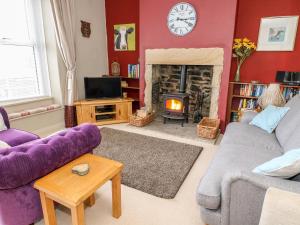 uma sala de estar com um sofá roxo e uma lareira em Canalside Cottage em Kildwick