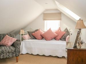 Un dormitorio con una cama con almohadas rosas y una ventana en Woodend Annexe, en Slindon