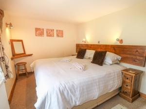 Un dormitorio con una gran cama blanca con cabecero de madera. en Fletchers Barn, en Alderwasley