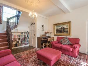 a living room with two red couches and a piano at The Old Schoolhouse and Cottage in Bishops Castle