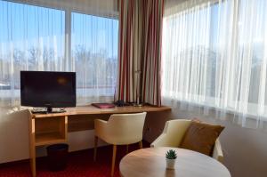 a room with a desk with a television and a table at Hotel Römerhof in Tulln