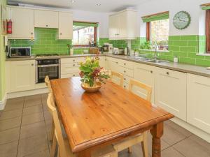 a kitchen with a wooden table and green tiles at Salter Rake Gate Cottage in Walsden