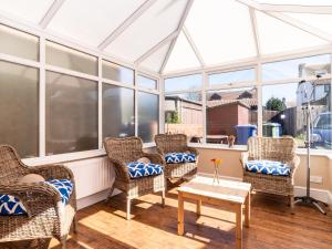 a screened in porch with wicker chairs and a table at Tomeg in Amble