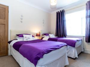 two beds in a room with purple and white at Tomeg in Amble
