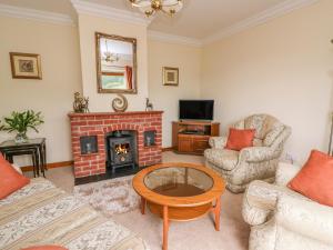 uma sala de estar com uma lareira de tijolos e uma mesa em Drainbyrion Farm House em Van