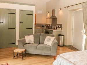 a living room with a couch and a kitchen at Tawny Owl Barn in Shipdham