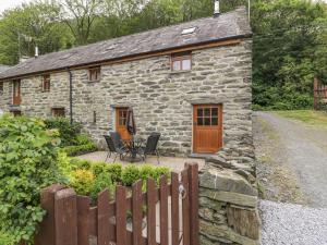 a stone cottage with a table and chairs in front of it at Hendoll Cottage 2 in Fairbourne