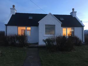 uma casa branca com as luzes acesas à noite em Amber's Cottage em Staffin