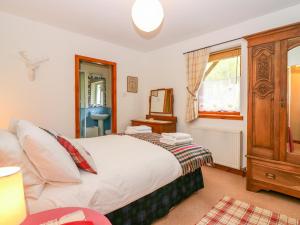 a bedroom with a bed and a dresser and a window at Little Danescroft in Corpach