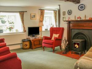 a living room with a red chair and a fireplace at Penymaes in Chirk
