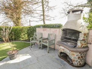 un horno al aire libre con 2 sillas y una mesa en Eden Lodge, en Bardsea