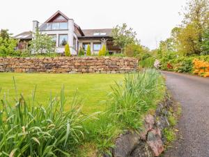 a house with a stone wall and a road at Little Danescroft in Corpach