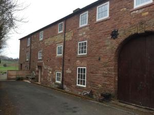 um grande edifício de tijolos vermelhos com garagem em Carleton Mill with open views to River Eden on the outskirts of Carlisle & 20 mins to Ullswater em Carlisle