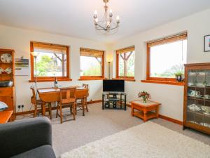a living room with a table and a dining room at Little Danescroft in Corpach