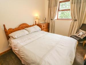 una camera da letto con un grande letto bianco e una finestra di Horrace Farm Cottage a Pennington