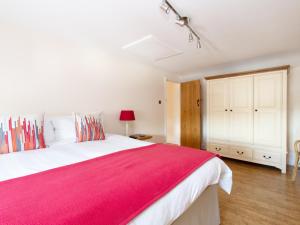 a bedroom with a large bed with a red blanket at The Gables Coach House in Burlton