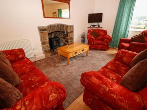 a living room with red couches and a fireplace at Buckinghams Leary Farm Cottage in Filleigh