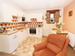 a kitchen with white cabinets and an orange chair at The Hideaway at The Barn in Tavernspite