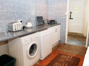 a kitchen with a washing machine and a sink at Buckinghams Leary Farm Cottage in Filleigh