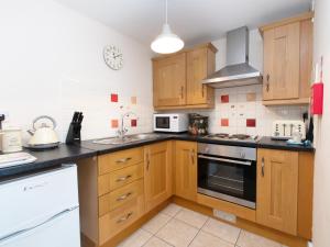 a kitchen with wooden cabinets and a stove top oven at The Gables Coach House in Burlton