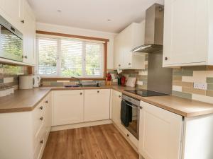 a kitchen with white cabinets and wooden floors at Isla Cottage in Rattray
