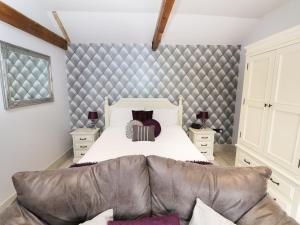 a bedroom with a large bed with a leather couch at Jack's Corner in Grimston