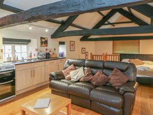 a living room with a leather couch and a kitchen at The Annex - Eden House in Edenhall