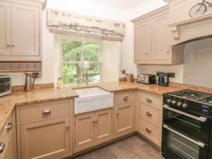 a kitchen with white cabinets and a window at The Tack Room Cottage in Ashover