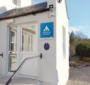 a sign on the side of a building with a door at Cairngorm Lodge Youth Hostel in Loch Morlich